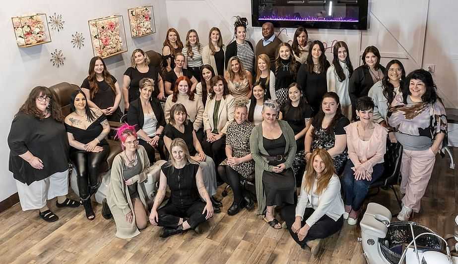 Group of smiling people posing in a room with floral artwork on the walls.