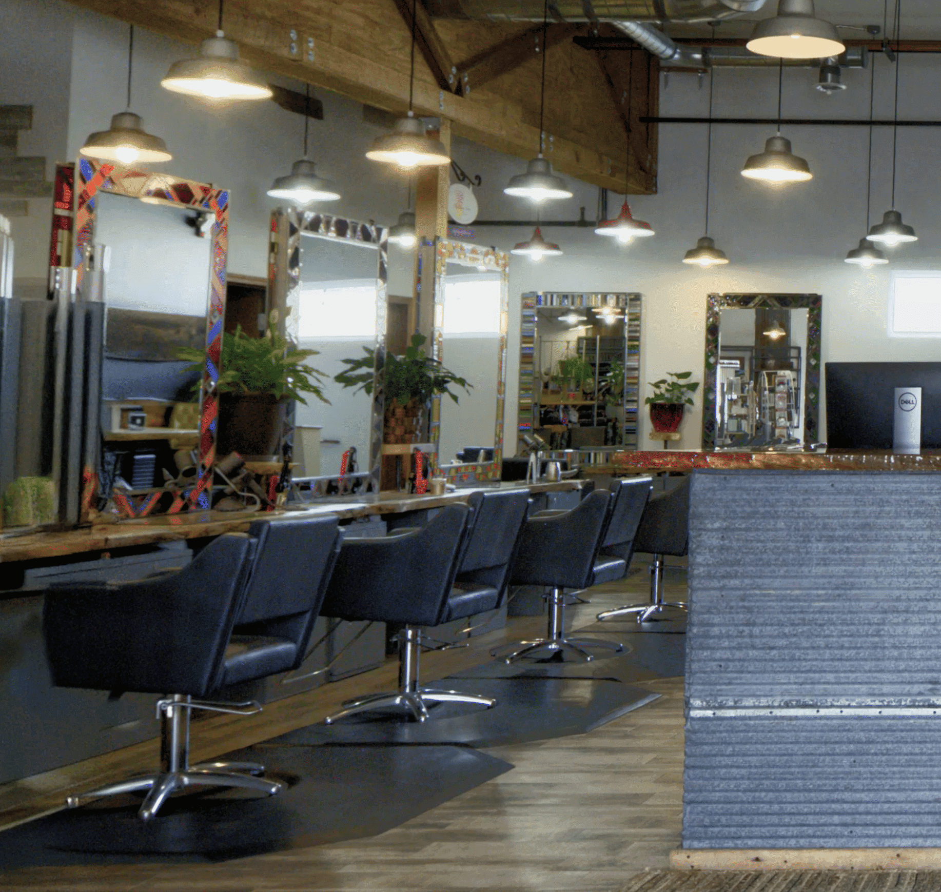 Modern hair salon interior with empty styling stations and industrial lighting.