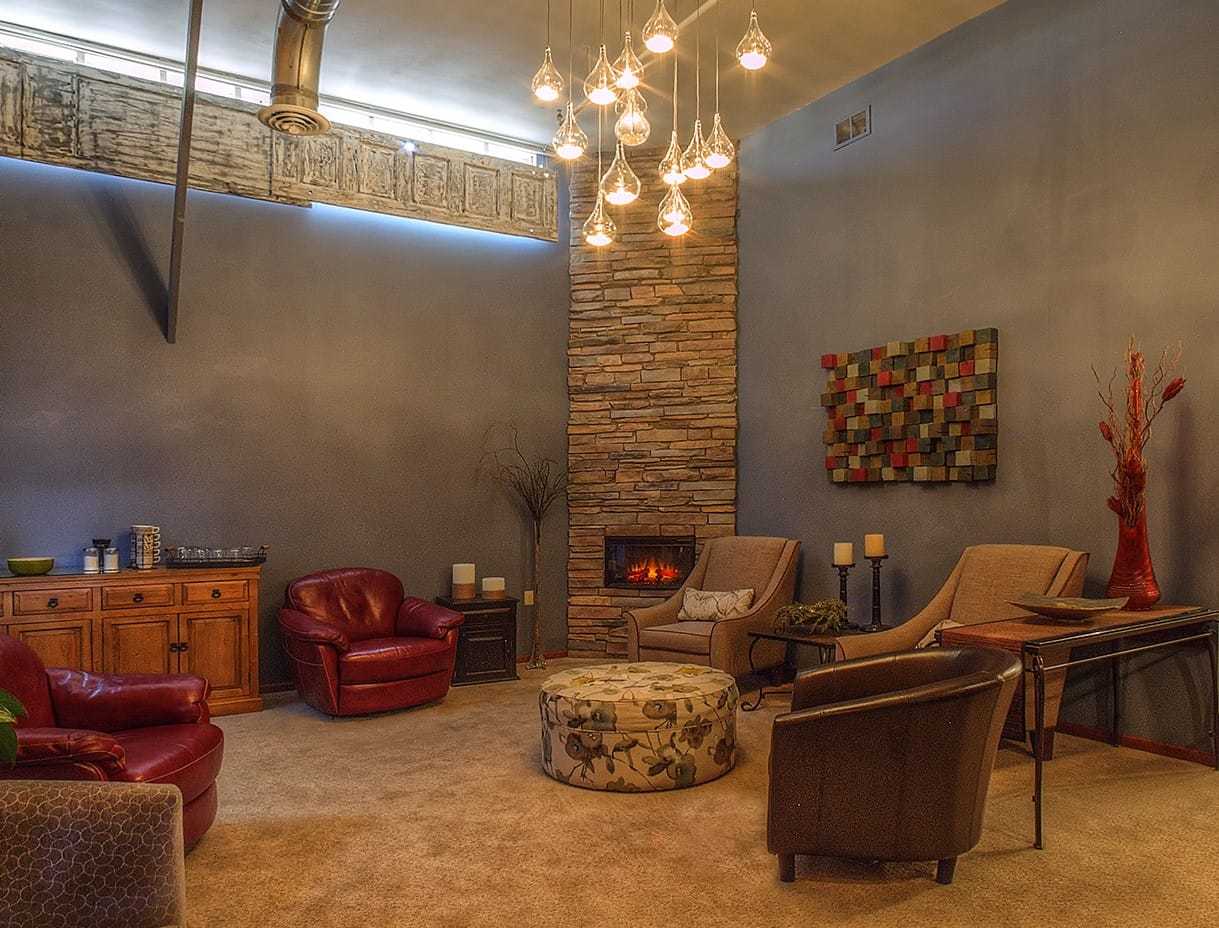 Cozy lounge with armchairs, fireplace, and modern decor under warm overhead lighting.