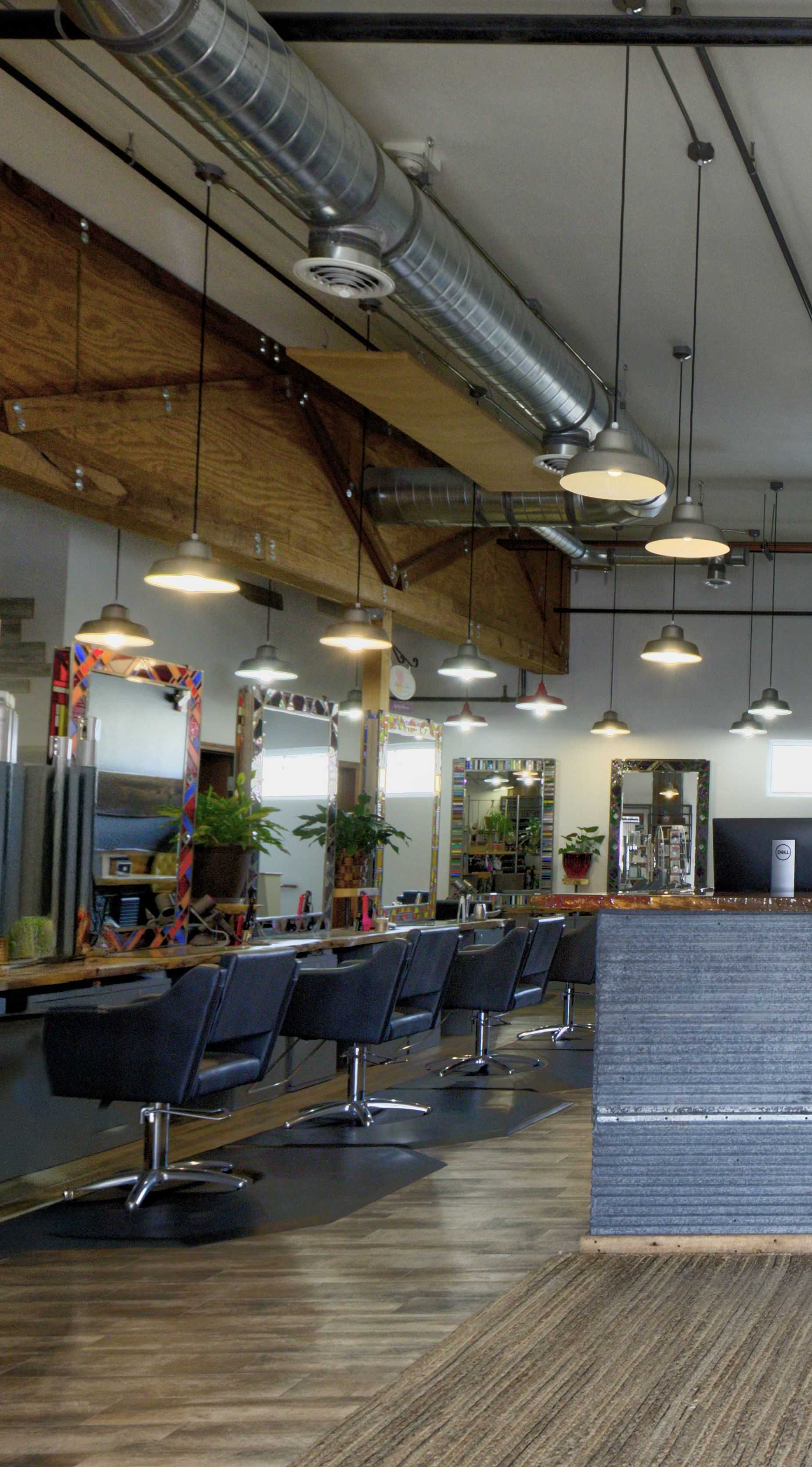 Modern hair salon interior with empty styling stations and industrial lighting.